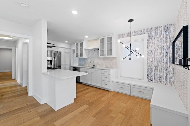 1701 Brentwood St, Austin, TX 78757 - kitchen featuring appliances with stainless steel finishes, white cabinetry, glass insert cabinets, light countertops, and light wood-style flooring