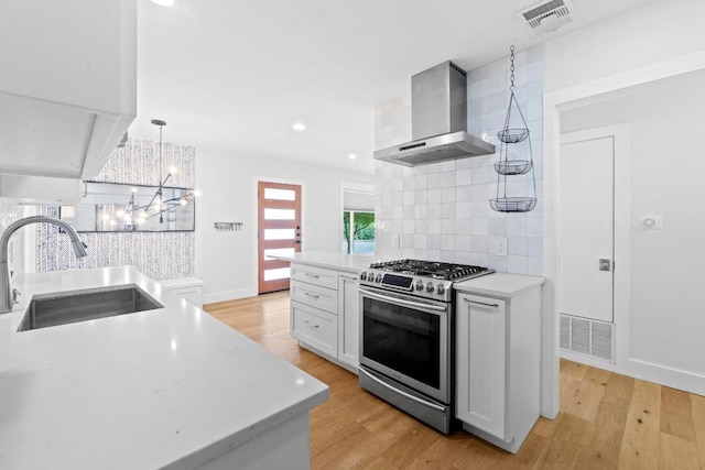 1701 Brentwood St, Austin, TX 78757 - kitchen featuring wall chimney range hood, stainless steel range with gas stovetop, backsplash, light wood-type flooring, and a chandelier