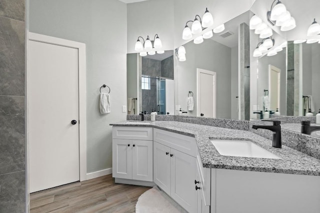 2134 Cervin Blvd, Austin, TX 78728 - bathroom featuring double vanity, a stall shower, wood finished floors, and a chandelier