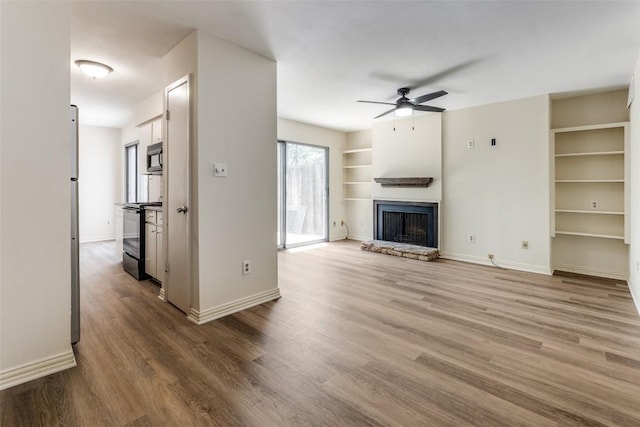 6910 Hart Ln Unit 807, Austin, TX 78731 - unfurnished living room with wood finished floors, ceiling fan, a fireplace, and built in features