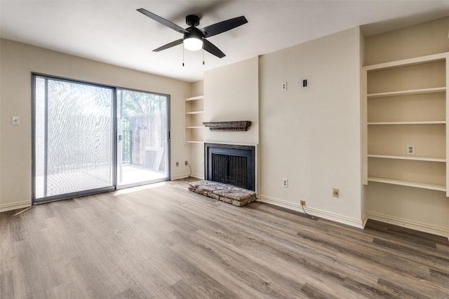 6910 Hart Ln Unit 807, Austin, TX 78731 - unfurnished living room featuring wood finished floors, built in shelves, a fireplace, and ceiling fan