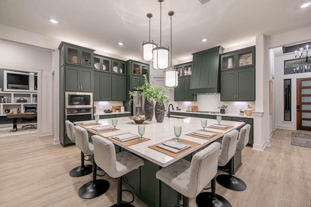 19125 Hopper Ln, Austin, TX 78738 - kitchen with appliances with stainless steel finishes, green cabinetry, light wood-style flooring, tasteful backsplash, and recessed lighting
