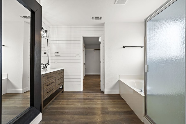 2208 Drue Ln, Cedar Park, TX 78613 - full bath featuring vanity, a walk in closet, a garden tub, wood finished floors, and a stall shower