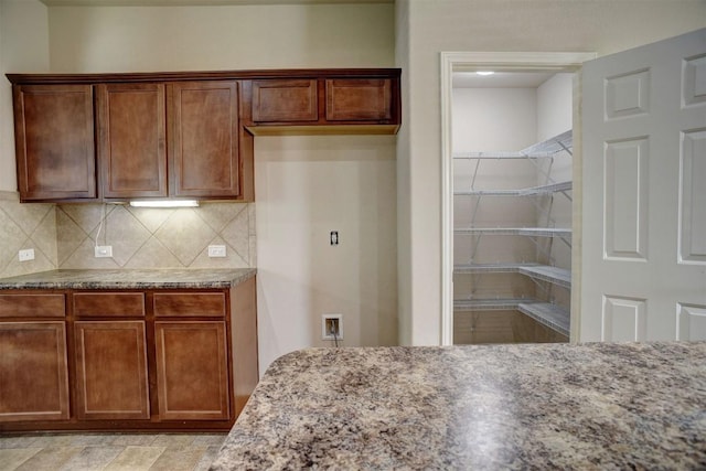 306 Grutsch Dr, Bastrop, TX 78602 - kitchen with light stone counters, decorative backsplash, and brown cabinetry