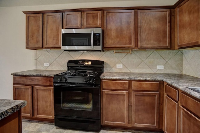 306 Grutsch Dr, Bastrop, TX 78602 - kitchen with stainless steel microwave, black range with gas stovetop, and decorative backsplash