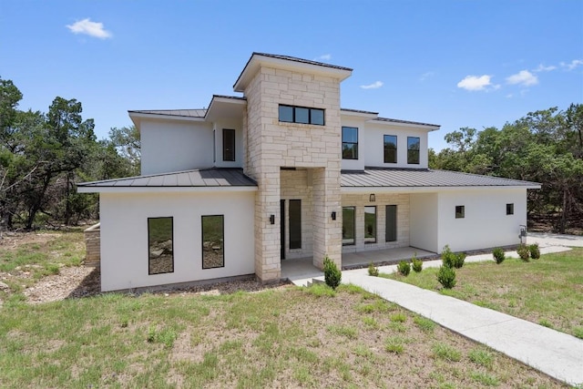 7705 Calcutta Run Dr, Jonestown, TX 78645 - view of front of house featuring a standing seam roof, a metal roof, a patio area, a front yard, and stucco siding