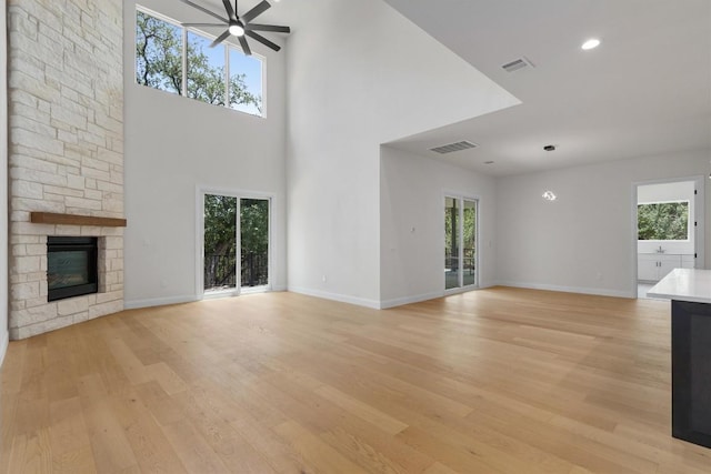 7705 Calcutta Run Dr, Jonestown, TX 78645 - unfurnished living room featuring plenty of natural light, light wood-style floors, a fireplace, a towering ceiling, and recessed lighting