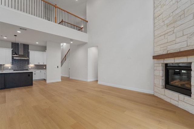 7705 Calcutta Run Dr, Jonestown, TX 78645 - unfurnished living room with light wood-style floors, a fireplace, a towering ceiling, stairway, and recessed lighting