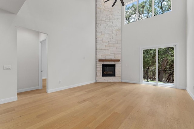 7705 Calcutta Run Dr, Jonestown, TX 78645 - unfurnished living room with a high ceiling, healthy amount of natural light, light wood-style floors, ceiling fan, and a stone fireplace