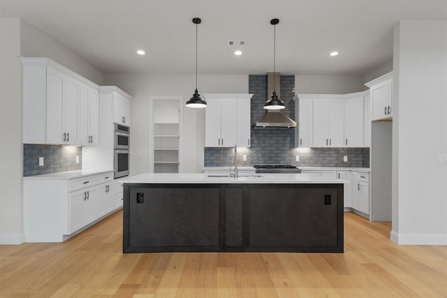 7705 Calcutta Run Dr, Jonestown, TX 78645 - kitchen with wall chimney exhaust hood, double oven, light countertops, light wood-type flooring, and recessed lighting