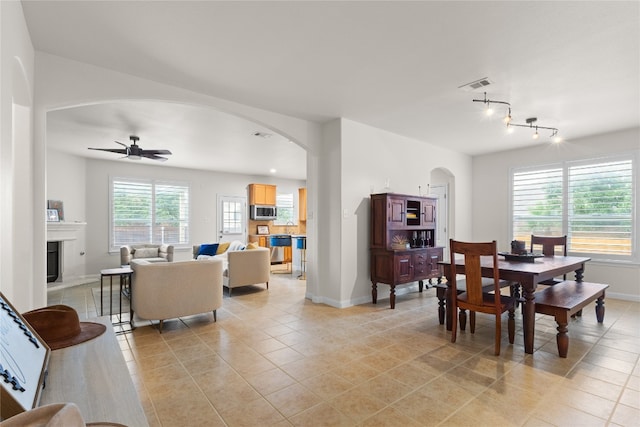 3308 Harvest Time Cv, Austin, TX 78754 - dining space with arched walkways, light tile patterned floors, a ceiling fan, a fireplace with raised hearth, and track lighting
