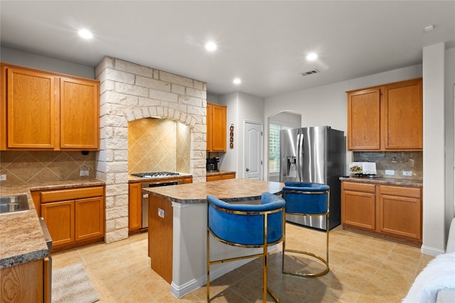 3308 Harvest Time Cv, Austin, TX 78754 - kitchen featuring stainless steel appliances, decorative backsplash, arched walkways, a kitchen island, and recessed lighting