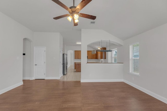 109 Inman Dr, Hutto, TX 78634 - unfurnished living room with a ceiling fan, arched walkways, vaulted ceiling, and light wood-type flooring