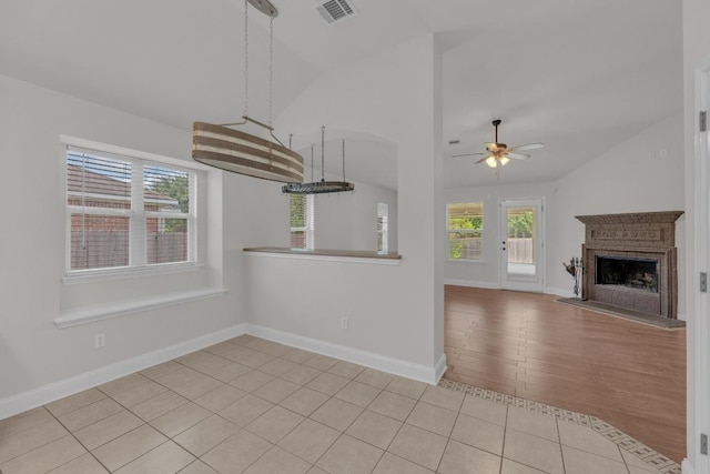 109 Inman Dr, Hutto, TX 78634 - kitchen featuring vaulted ceiling, ceiling fan, a fireplace with raised hearth, and light tile patterned floors