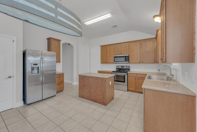 109 Inman Dr, Hutto, TX 78634 - kitchen featuring stainless steel appliances, arched walkways, light tile patterned floors, a center island, and light countertops