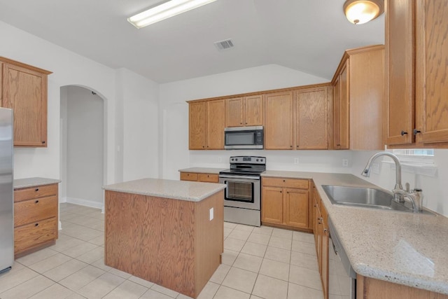 109 Inman Dr, Hutto, TX 78634 - kitchen featuring stainless steel appliances, arched walkways, a center island, light tile patterned flooring, and lofted ceiling