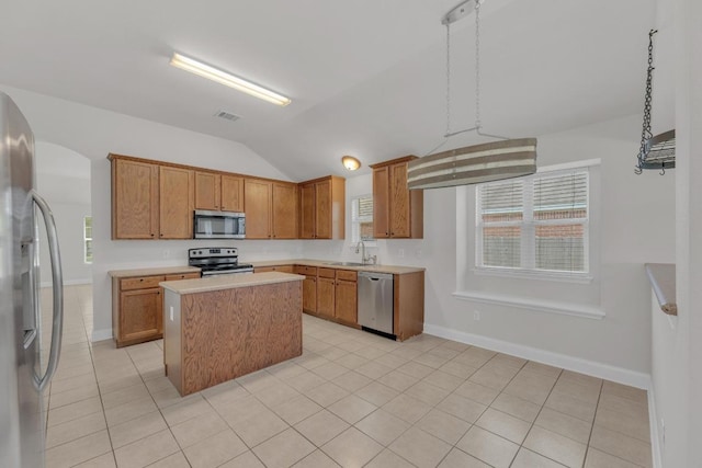 109 Inman Dr, Hutto, TX 78634 - kitchen featuring appliances with stainless steel finishes, lofted ceiling, a kitchen island, light countertops, and brown cabinets
