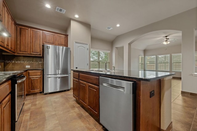 18712 Leigh Ln, Pflugerville, TX 78660 - kitchen featuring appliances with stainless steel finishes, a ceiling fan, brown cabinetry, recessed lighting, and dark stone counters