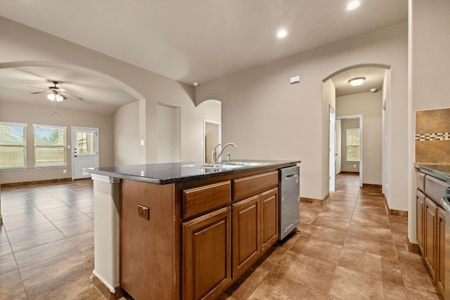 18712 Leigh Ln, Pflugerville, TX 78660 - kitchen with stainless steel dishwasher, a ceiling fan, a kitchen island with sink, arched walkways, and brown cabinetry