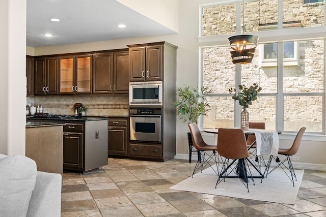 7204 Covered Bridge Dr, Austin, TX 78736 - kitchen featuring appliances with stainless steel finishes, dark countertops, decorative backsplash, stone tile flooring, and dark brown cabinets