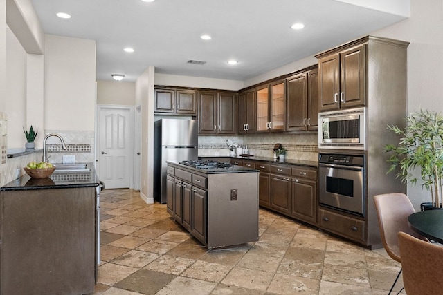7204 Covered Bridge Dr, Austin, TX 78736 - kitchen featuring stainless steel appliances, stone tile floors, tasteful backsplash, dark brown cabinets, and recessed lighting
