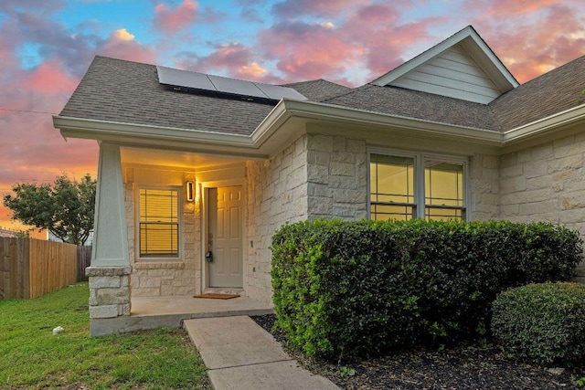 608 Timothy John Dr, Pflugerville, TX 78660 - exterior entry at dusk featuring a shingled roof, stone siding, and roof mounted solar panels