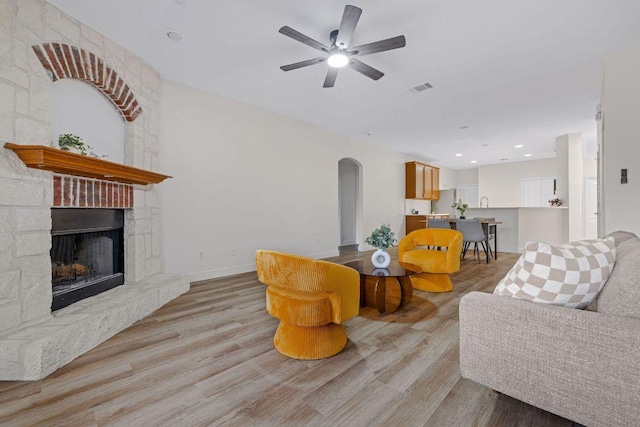 608 Timothy John Dr, Pflugerville, TX 78660 - living area featuring arched walkways, light wood finished floors, ceiling fan, a fireplace, and recessed lighting