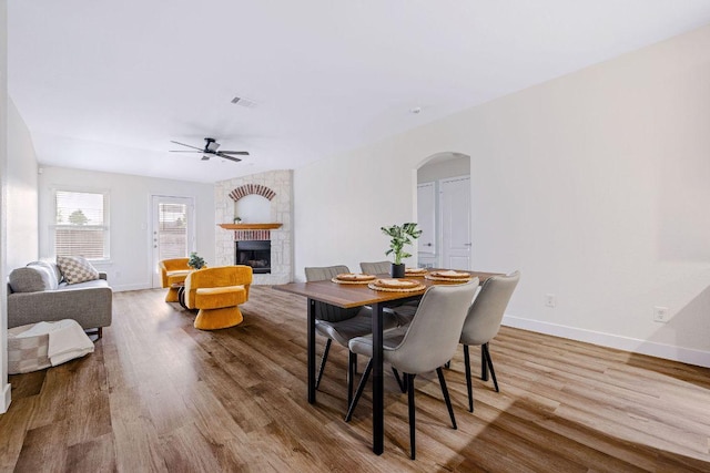 608 Timothy John Dr, Pflugerville, TX 78660 - dining space featuring arched walkways, a large fireplace, ceiling fan, and wood finished floors