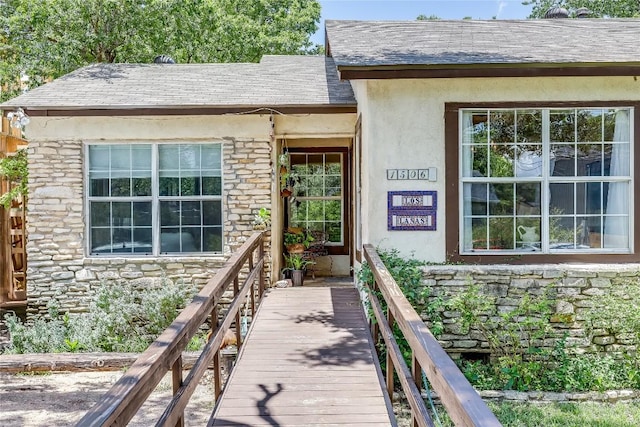 1506 Alguno Rd, Austin, TX 78757 - view of exterior entry featuring stone siding, roof with shingles, and stucco siding