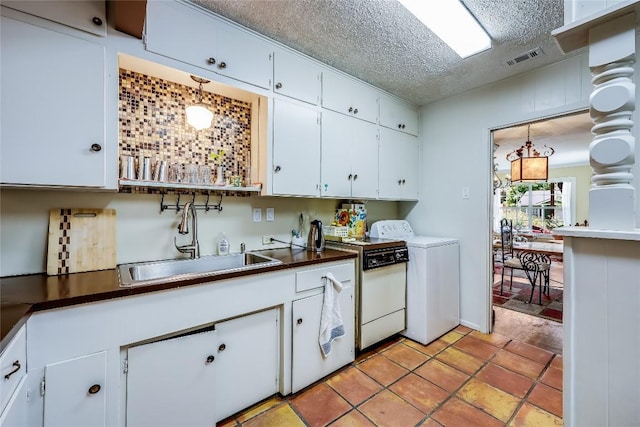1506 Alguno Rd, Austin, TX 78757 - kitchen featuring washer / dryer, white cabinetry, dark countertops, a textured ceiling, and hanging light fixtures