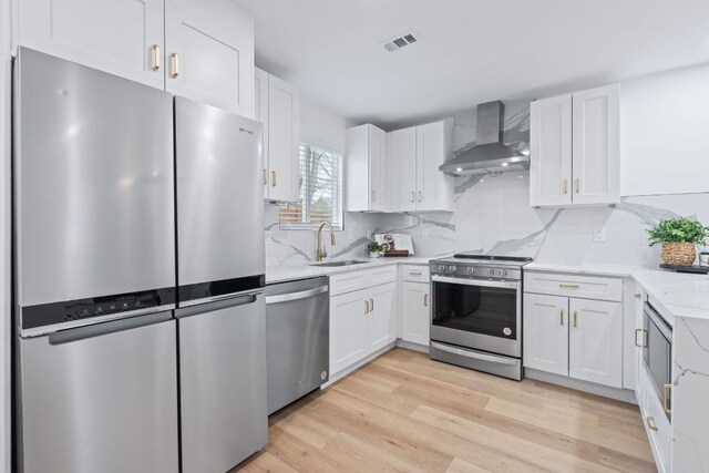 2706 Wheless Ln Bldg 5, Austin, TX 78723 - kitchen featuring stainless steel appliances, wall chimney exhaust hood, white cabinetry, and light wood-style floors