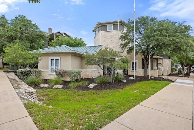2320 Gracy Farms Ln Unit 323, Austin, TX 78758 - view of home's exterior with stone siding, a standing seam roof, stucco siding, and a yard