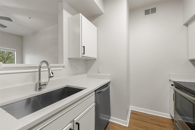 2320 Gracy Farms Ln Unit 323, Austin, TX 78758 - kitchen featuring appliances with stainless steel finishes, wood finished floors, white cabinetry, light countertops, and ceiling fan