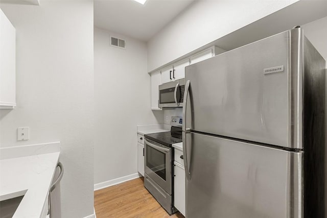 2320 Gracy Farms Ln Unit 323, Austin, TX 78758 - kitchen with appliances with stainless steel finishes, white cabinets, and light wood-style floors