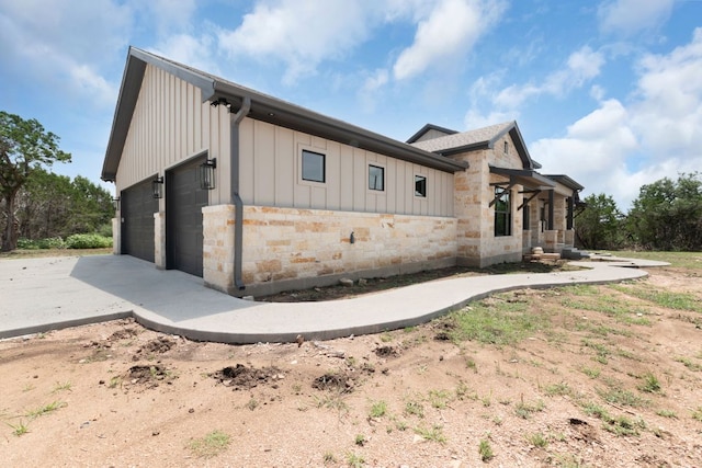 209 Burnet Oaks Dr, Burnet, TX 78611 - view of side of home featuring stone siding, board and batten siding, driveway, and an attached garage