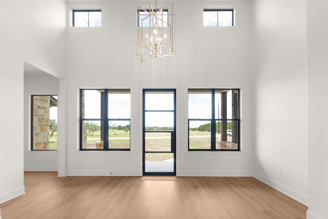 209 Burnet Oaks Dr, Burnet, TX 78611 - unfurnished living room featuring a towering ceiling, light wood-style flooring, and a chandelier