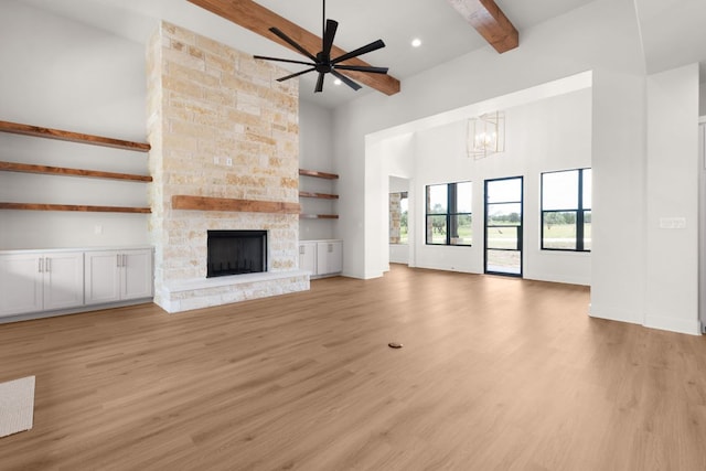 209 Burnet Oaks Dr, Burnet, TX 78611 - unfurnished living room with beam ceiling, ceiling fan, a chandelier, light wood finished floors, and a stone fireplace
