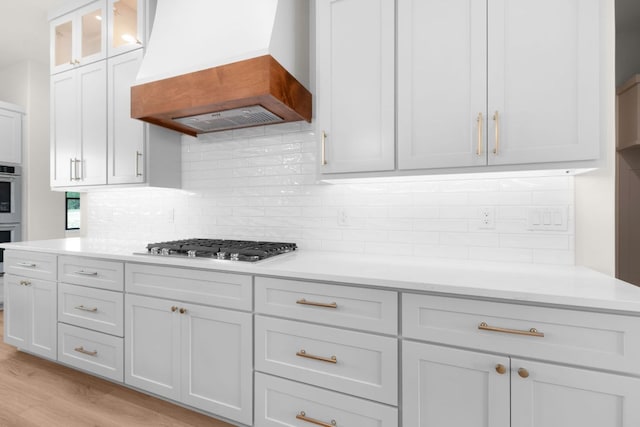 209 Burnet Oaks Dr, Burnet, TX 78611 - kitchen with premium range hood, appliances with stainless steel finishes, light countertops, decorative backsplash, and light wood finished floors