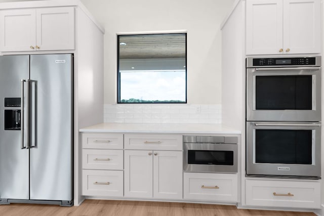 209 Burnet Oaks Dr, Burnet, TX 78611 - kitchen with appliances with stainless steel finishes, light countertops, backsplash, light wood-style flooring, and white cabinets