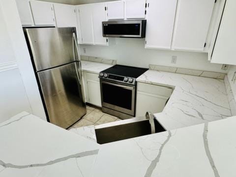 2320 Gracy Farms Ln Unit 1432, Austin, TX 78758 - kitchen featuring appliances with stainless steel finishes, light stone counters, and white cabinetry