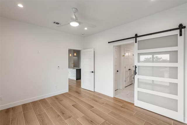 18924 Peckham Dr, Point Venture, TX 78645 - unfurnished room featuring a barn door, light wood-style floors, a ceiling fan, and recessed lighting