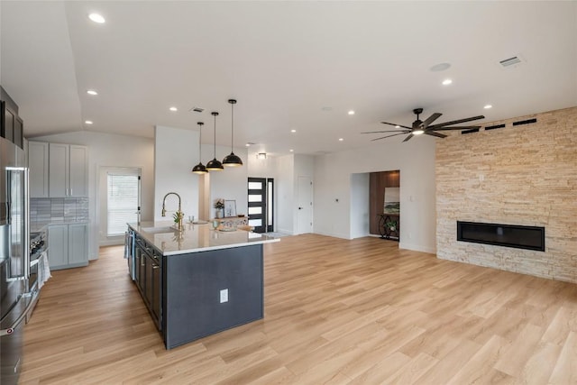 18924 Peckham Dr, Point Venture, TX 78645 - kitchen with light countertops, a kitchen island with sink, a ceiling fan, open floor plan, and a fireplace
