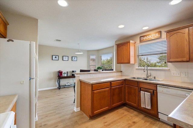 327 Lakemont Dr, Hutto, TX 78634 - kitchen featuring white appliances, a peninsula, light wood-type flooring, healthy amount of natural light, and recessed lighting