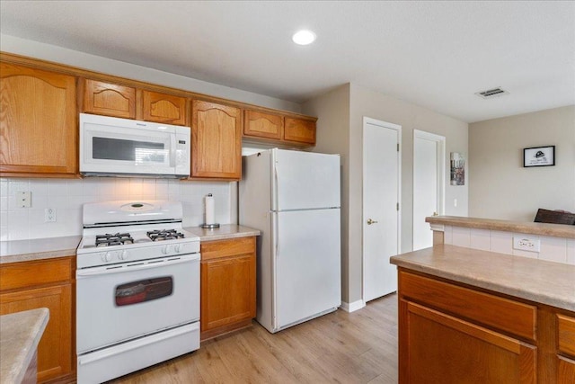 327 Lakemont Dr, Hutto, TX 78634 - kitchen featuring white appliances, light wood-style flooring, brown cabinetry, backsplash, and recessed lighting