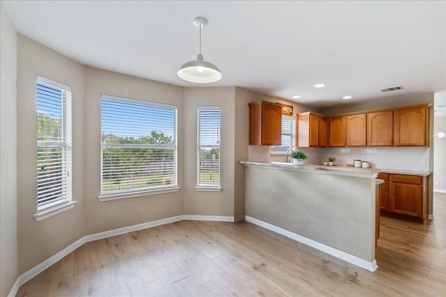 327 Lakemont Dr, Hutto, TX 78634 - kitchen with light wood-style floors, healthy amount of natural light, light countertops, brown cabinetry, and recessed lighting