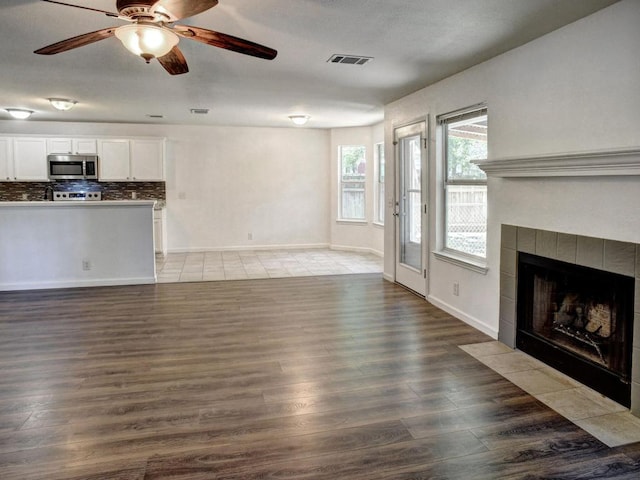 117 High Point Blvd, Cedar Creek, TX 78612 - unfurnished living room with a fireplace, wood finished floors, and a ceiling fan