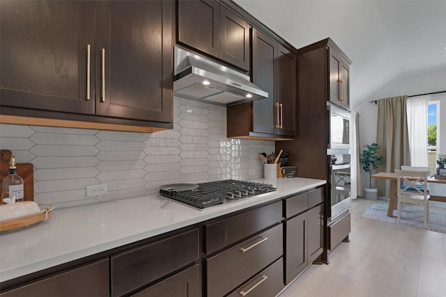 20240 Smedley Dr, Pflugerville, TX 78660 - kitchen featuring stainless steel gas cooktop, under cabinet range hood, dark brown cabinetry, vaulted ceiling, and backsplash