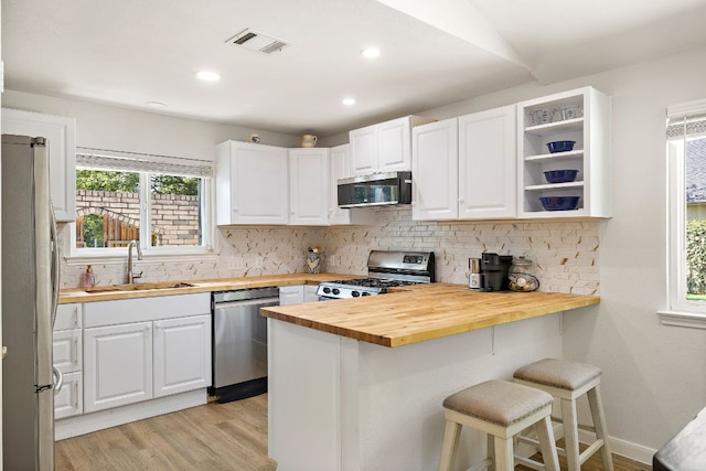 15002 Wells Port Dr, Austin, TX 78728 - kitchen featuring butcher block countertops, stainless steel appliances, a peninsula, a kitchen bar, and light wood finished floors