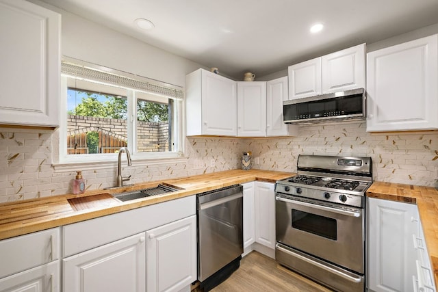 15002 Wells Port Dr, Austin, TX 78728 - kitchen featuring wooden counters, appliances with stainless steel finishes, decorative backsplash, and white cabinets