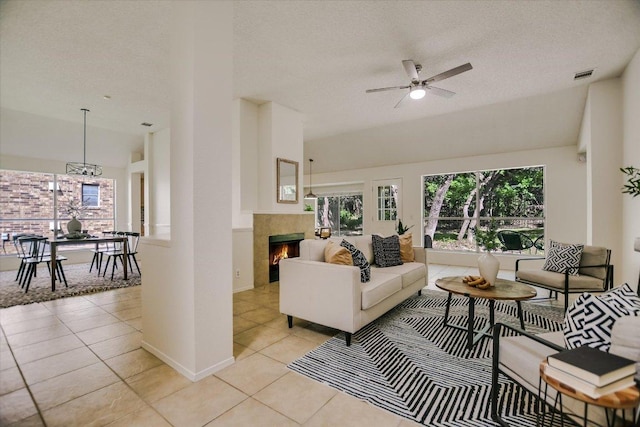 3413 Latimer Dr, Austin, TX 78732 - living room featuring light tile patterned floors, a ceiling fan, a textured ceiling, and a tiled fireplace